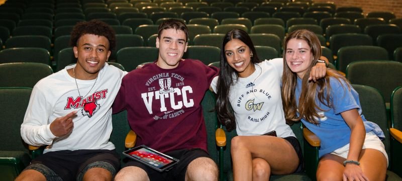 four students sitting in auditorium