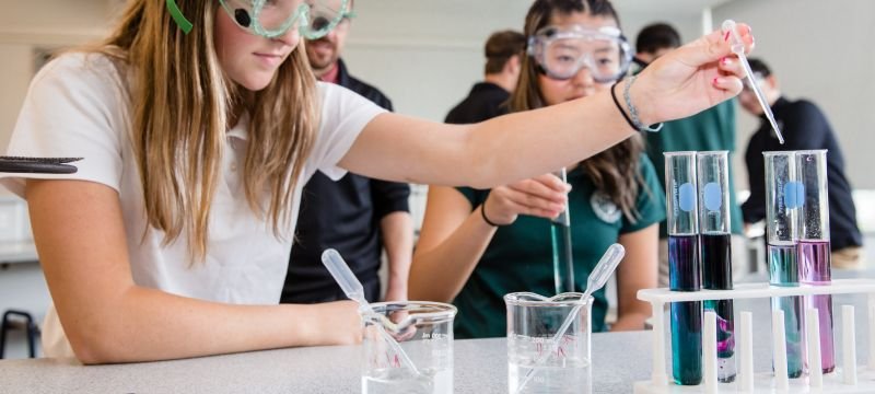 NWC students wearing safety goggles and putting liquid into test tubes